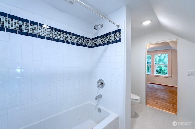 bathroom featuring hardwood / wood-style flooring, toilet, tiled shower / bath, and vaulted ceiling