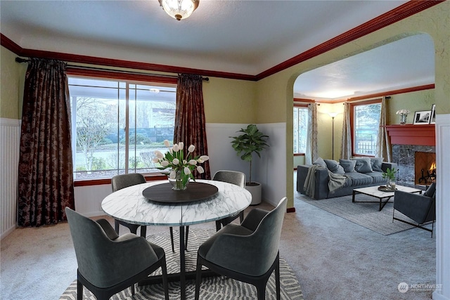 carpeted dining space featuring a premium fireplace and ornamental molding