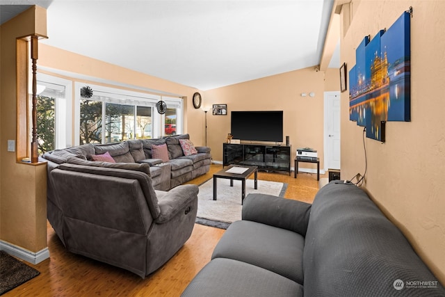 living room featuring lofted ceiling with beams and light hardwood / wood-style floors