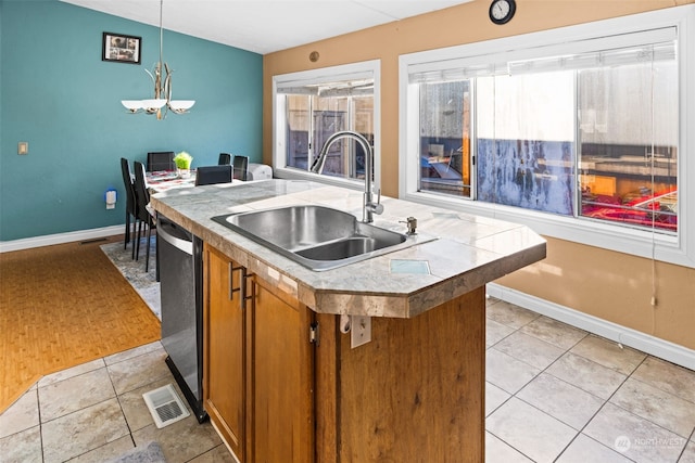 kitchen with a kitchen island with sink, an inviting chandelier, sink, hanging light fixtures, and stainless steel dishwasher