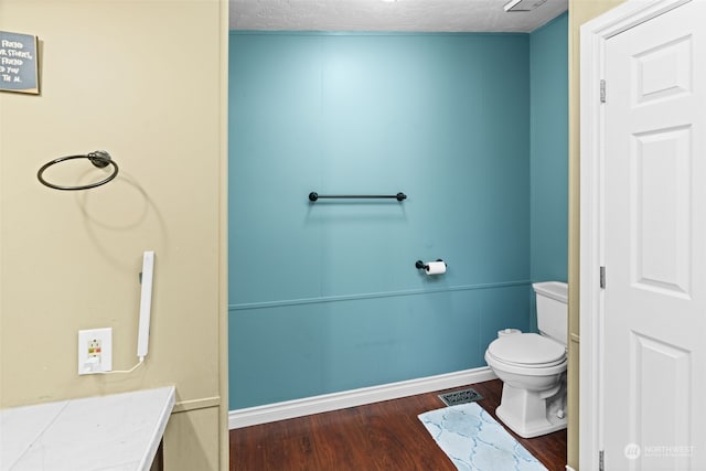 bathroom featuring hardwood / wood-style flooring, toilet, and a textured ceiling