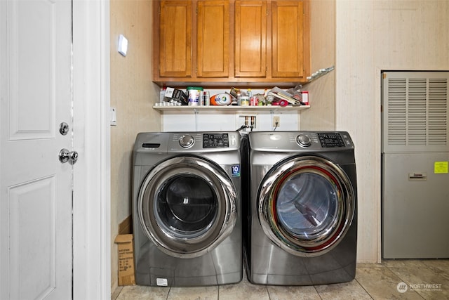 laundry room with washer and clothes dryer, light tile patterned flooring, and cabinets