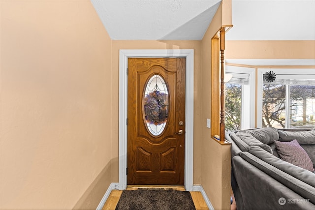 entrance foyer featuring a textured ceiling, light hardwood / wood-style flooring, and lofted ceiling