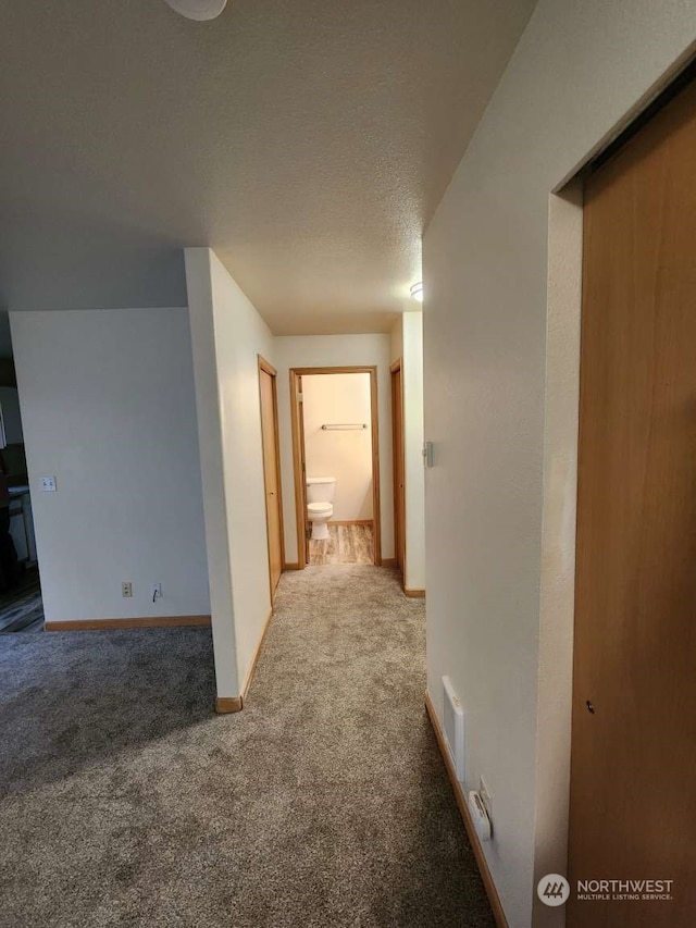 hallway featuring carpet floors and a textured ceiling