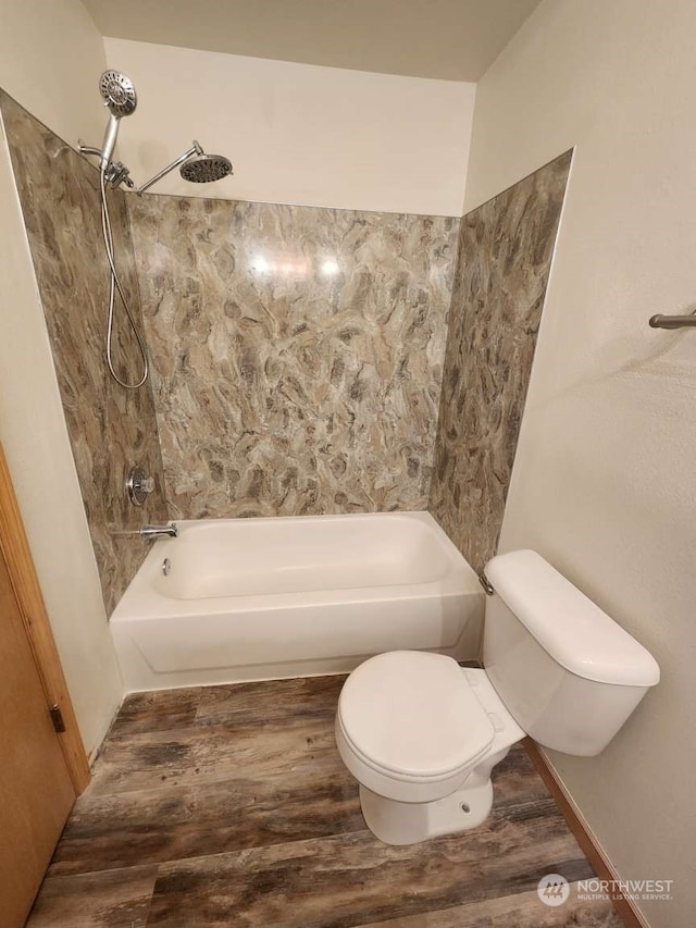 bathroom with hardwood / wood-style floors, toilet, and tiled shower / bath