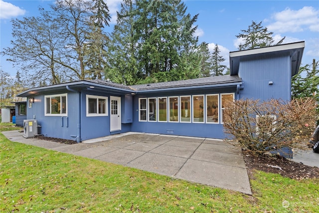 rear view of property with a yard, a patio, and a sunroom