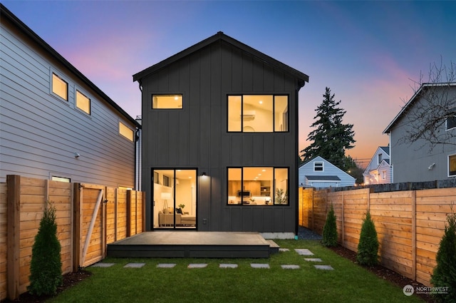 back house at dusk featuring a yard and a wooden deck