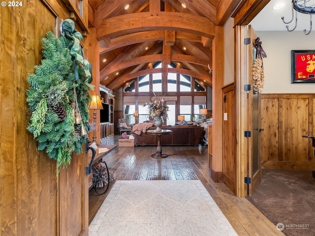 foyer entrance with vaulted ceiling with beams, wood walls, and hardwood / wood-style flooring