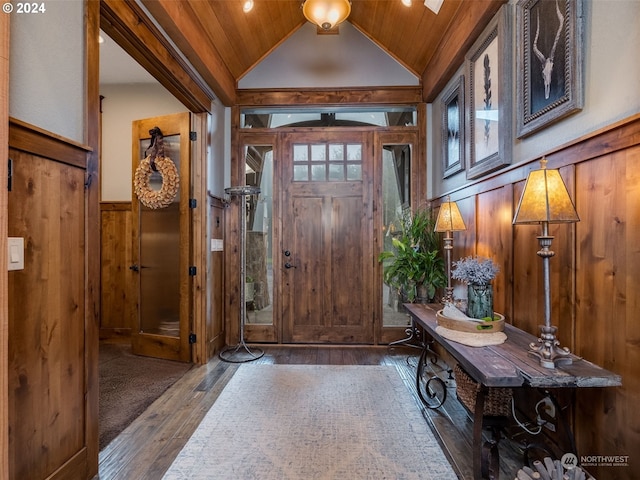 entrance foyer with wood walls, lofted ceiling, dark wood-type flooring, and wooden ceiling