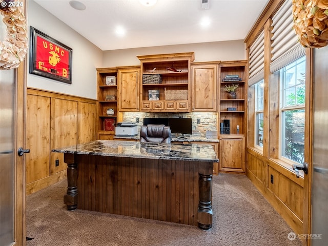 carpeted office featuring built in desk and wooden walls