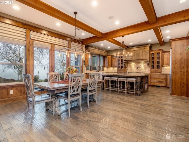 dining space with a chandelier, beam ceiling, and wood-type flooring