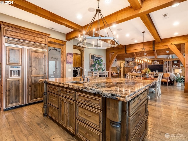 kitchen featuring decorative light fixtures, a spacious island, paneled fridge, and light wood-type flooring