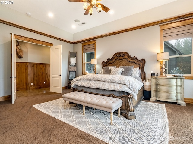 carpeted bedroom featuring ceiling fan and wood walls