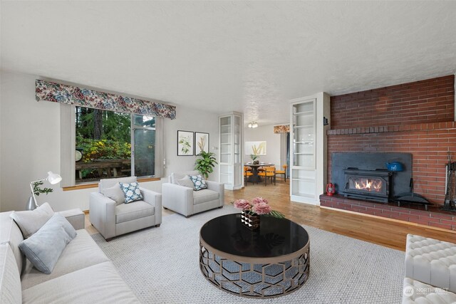 living room featuring french doors, a textured ceiling, hardwood / wood-style flooring, and a brick fireplace