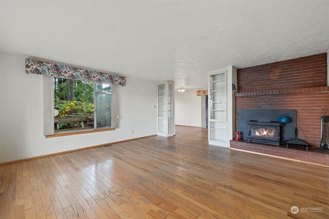 unfurnished living room with a large fireplace, wood-type flooring, a textured ceiling, and french doors