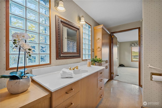 bathroom with a wealth of natural light, vanity, and a textured ceiling