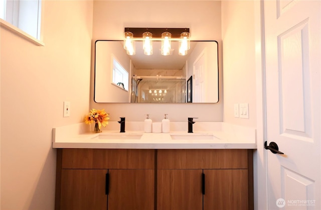 bathroom with double vanity, a shower with door, and a sink