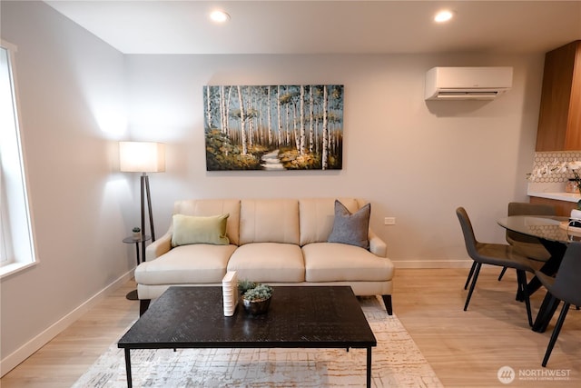 living area with a wall mounted AC, recessed lighting, light wood-style flooring, and baseboards