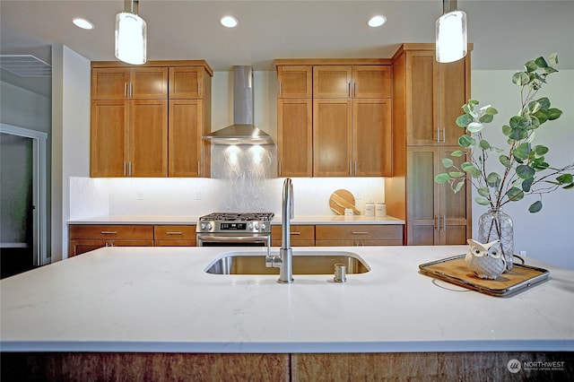 kitchen featuring decorative light fixtures, wall chimney range hood, sink, and high end range