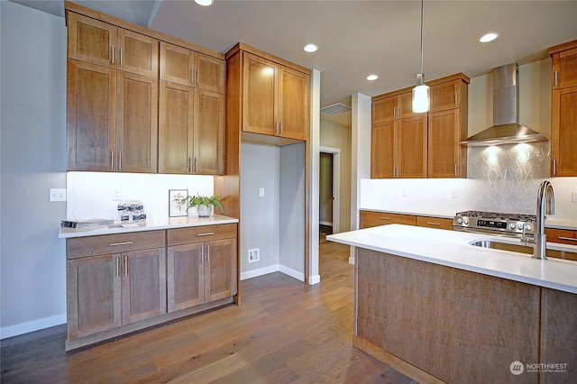 kitchen featuring sink, wall chimney range hood, tasteful backsplash, dark hardwood / wood-style flooring, and pendant lighting