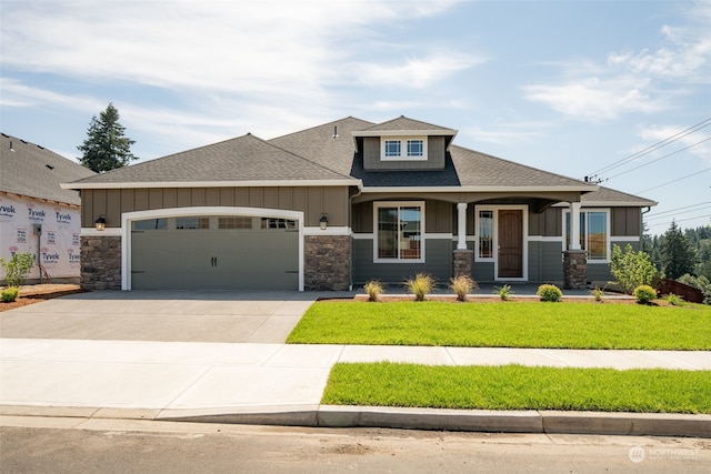 view of front facade with covered porch, a garage, and a front lawn