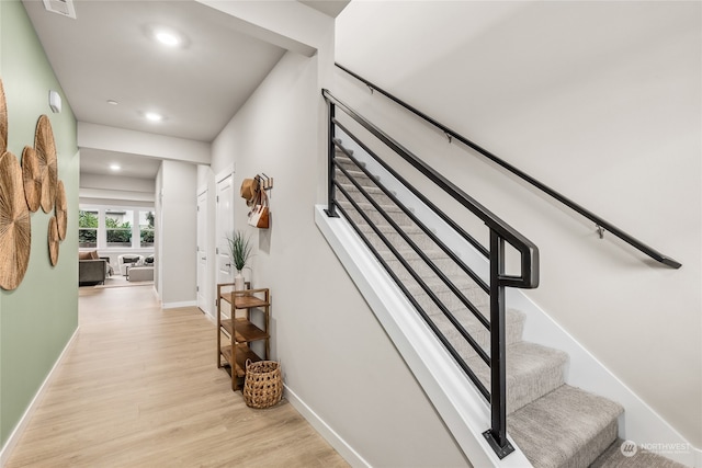 hallway featuring recessed lighting, stairs, light wood-type flooring, and baseboards