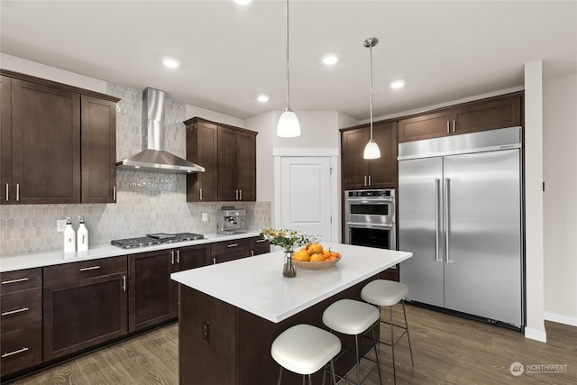 kitchen with backsplash, dark brown cabinetry, appliances with stainless steel finishes, and wall chimney range hood