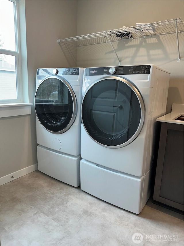 washroom featuring cabinet space, baseboards, and separate washer and dryer