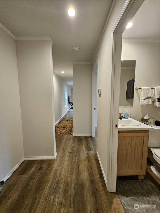 hall featuring dark hardwood / wood-style flooring, crown molding, and sink