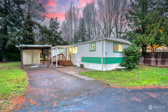 manufactured / mobile home with a carport and a lawn