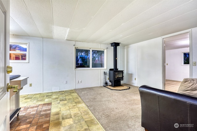 living room with carpet, a wood stove, and a textured ceiling