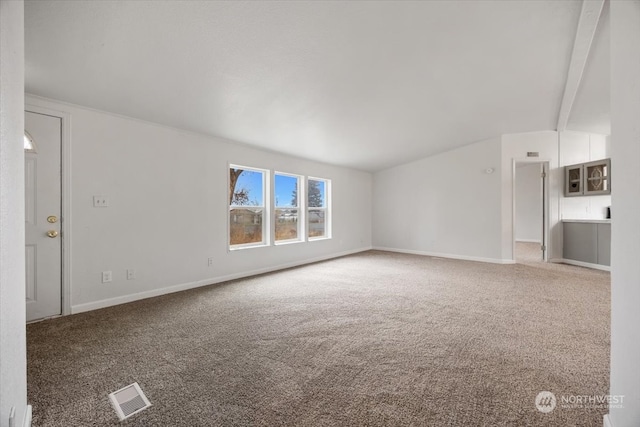 unfurnished living room featuring vaulted ceiling with beams and carpet floors