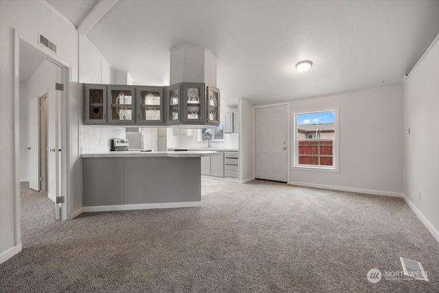 kitchen featuring kitchen peninsula, light carpet, and vaulted ceiling