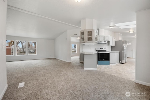 kitchen featuring white cabinetry, stainless steel appliances, vaulted ceiling, and light carpet