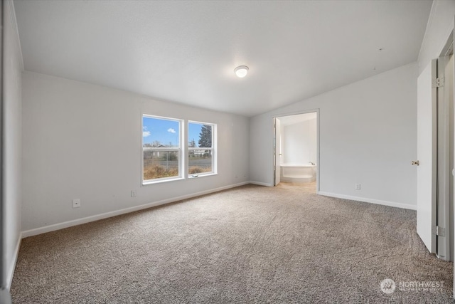 unfurnished bedroom featuring vaulted ceiling, carpet floors, and ensuite bath