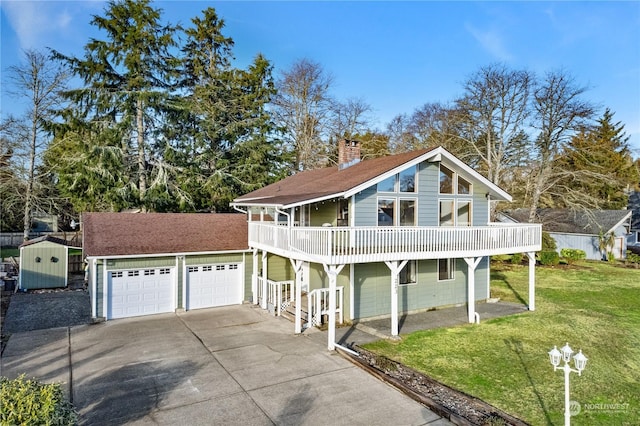 view of property featuring a front yard, a balcony, a storage unit, and a garage