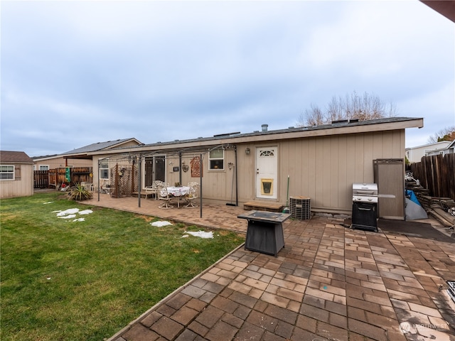 back of property featuring a lawn, a patio area, and a fire pit