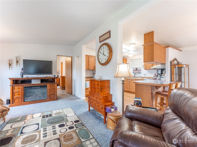 living room with lofted ceiling, light colored carpet, and sink