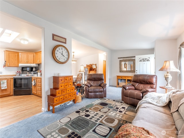 carpeted living room with lofted ceiling with skylight