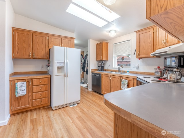 kitchen with vaulted ceiling with skylight, black appliances, light hardwood / wood-style floors, sink, and kitchen peninsula