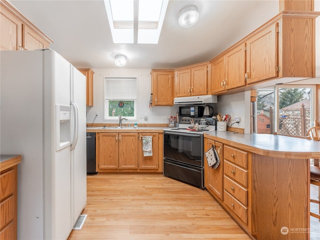 kitchen with a breakfast bar, sink, black dishwasher, range with electric cooktop, and white fridge with ice dispenser