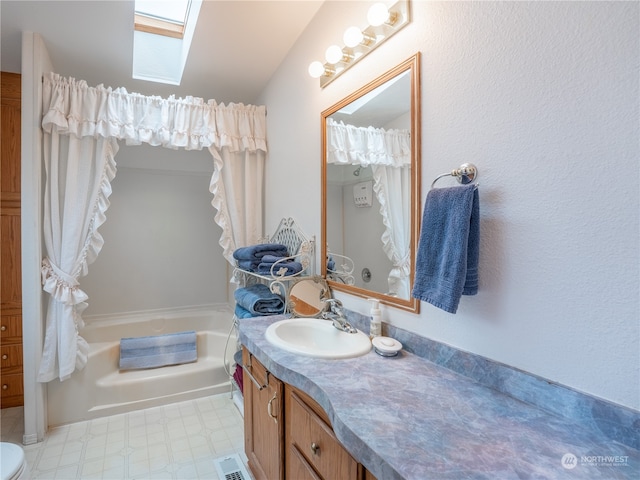 bathroom with a tub to relax in, vanity, and a skylight