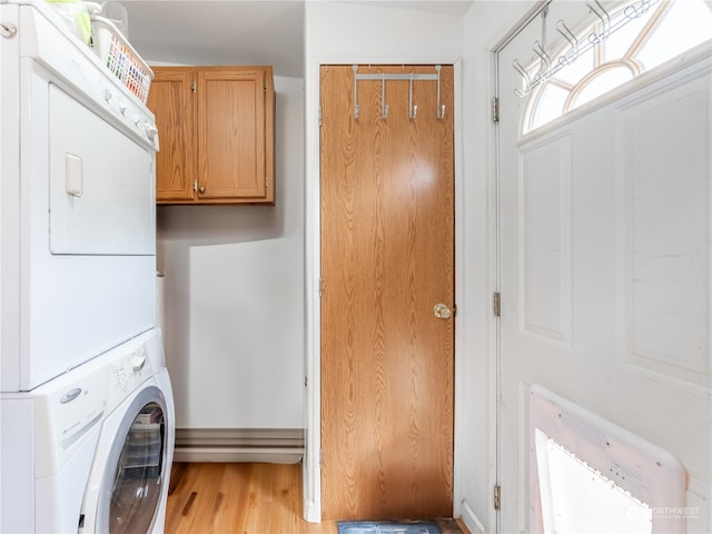 laundry area with stacked washer / dryer, light hardwood / wood-style flooring, and cabinets