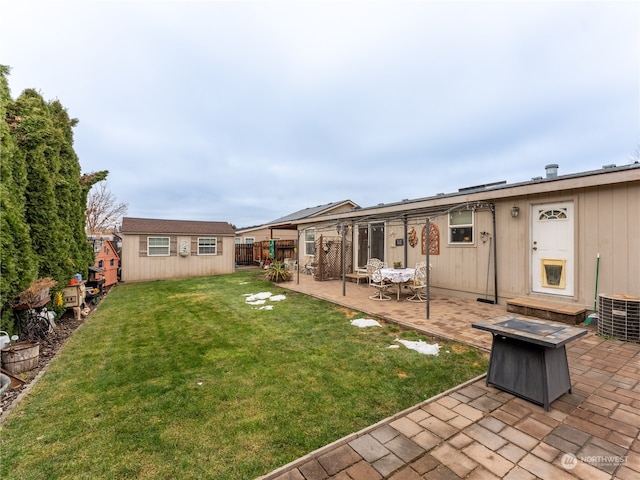 rear view of house featuring a patio area, an outdoor fire pit, a lawn, an outdoor structure, and central air condition unit