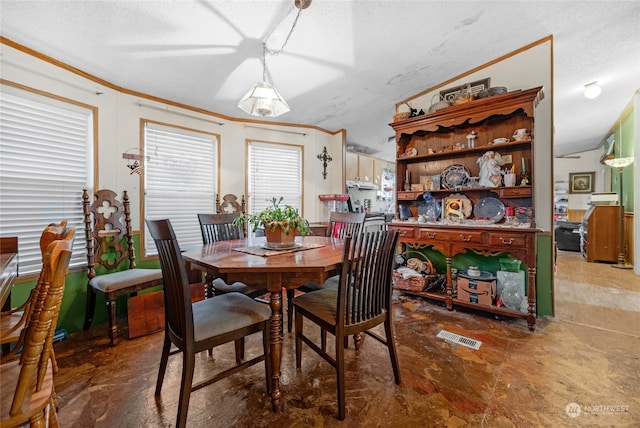 dining area featuring ornamental molding, a textured ceiling, and vaulted ceiling