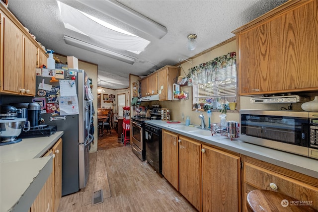 kitchen with sink, stainless steel appliances, ventilation hood, a textured ceiling, and light wood-type flooring