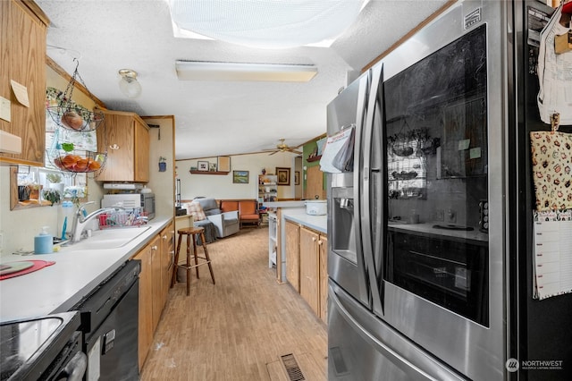 kitchen featuring lofted ceiling, sink, light wood-type flooring, a textured ceiling, and appliances with stainless steel finishes