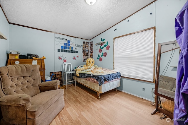 bedroom with a textured ceiling, light hardwood / wood-style floors, and ornamental molding