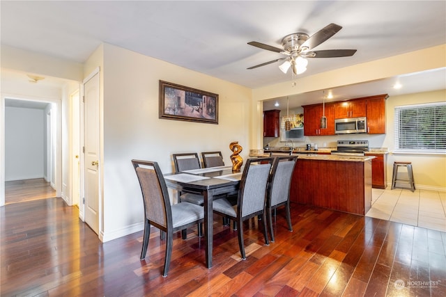 dining area with dark hardwood / wood-style flooring, ceiling fan, and sink