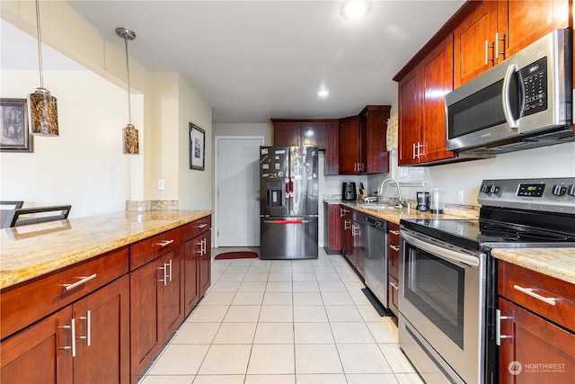 kitchen with appliances with stainless steel finishes, light stone counters, pendant lighting, and sink